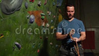 一名登山者在攀爬墙的背景下准备设备。 登山用编织结.