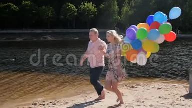 慢动作<strong>视频</strong>快乐的年轻夫妇拿着一大堆<strong>气球</strong>在海滩上奔跑