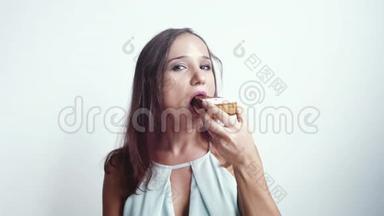 年轻漂亮的黑发女人在白色背景下吃一个美味的蛋糕。 慢动作。 3840x2160