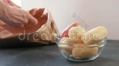 一碗土豆。 削皮土豆。 男人的手`清理土豆在一个生态袋的背景。