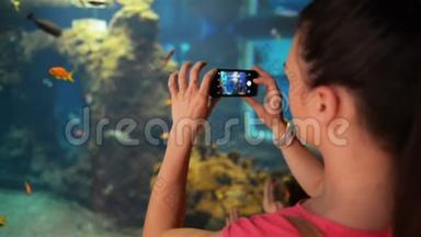 小女孩正在水族馆拍照。 她拿着手机拍照。