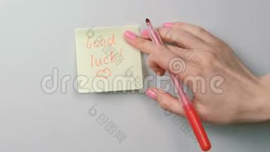 特写女人`手贴黄色贴纸纸，上面写着好运和绘画的心。