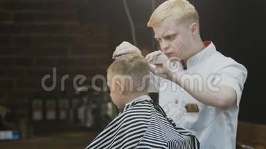 理发店。 时髦的小男孩在理发店理发。 一个漂亮的男孩和一个时尚的理发师理发