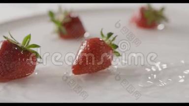 特写成熟的红色草莓果实<strong>落入</strong>一盘水中，溅起水花和水珠.. 几个浆果就在上面