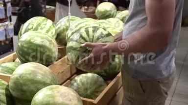 主题<strong>养生</strong>与天然美食.. 一个高加索人的特写`他的手握着，在超市的盒子里挑选一个西瓜。