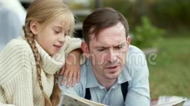 小女孩<strong>坐</strong>着<strong>拥</strong>抱她的父亲，读一本书。