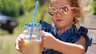 阳光明媚的<strong>风天</strong>，戴太阳镜的小女孩在公园里喝冰沙