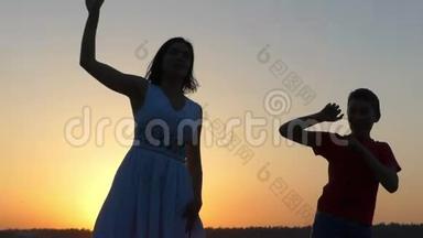 一个男孩和一个年轻的女人在日落时快乐地跳舞