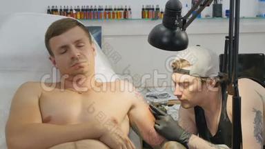 专业纹身师在纹身沙龙里`人手上做纹身