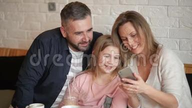 《幸福家庭在Smarthphone Indoors上做自拍》的肖像。 他们在咖啡厅度过这美好的一天。