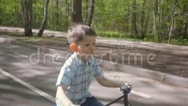 在柏油路骑自行车的小男孩。 可爱的男孩在自行车道上学骑自行车。