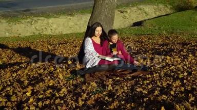 妈妈和女儿坐在树<strong>下</strong>看书。他们说得很好。妈妈和女儿在秋林里。他们是