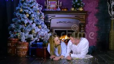 一对年轻夫妇在壁炉地毯上度过了一个圣诞夜。 新年庆祝理念..