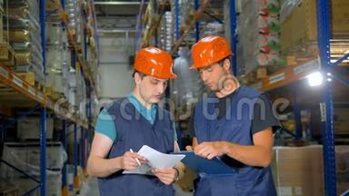 两名仓库工人讨论在储存架附近的<strong>工作计划</strong>。