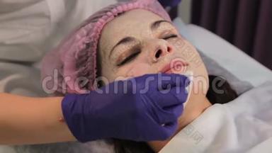 戴着手套的手从女人脸上摘下`面具。 治疗后皮肤发红，刺激。 特写