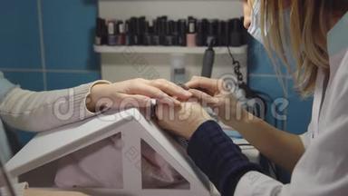 美甲大师在美容院用美甲钳治疗年轻顾客的角质层