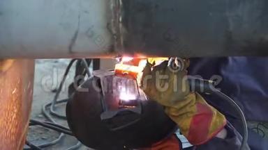 一名焊工在俄罗斯的炼油厂用手工电弧焊接工艺管道。 焊接接头。