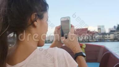 年轻快乐的<strong>旅游</strong>女孩在河上的船上航行，在手机上拍摄视频。 <strong>泰国曼谷</strong>。 4K，慢动作。