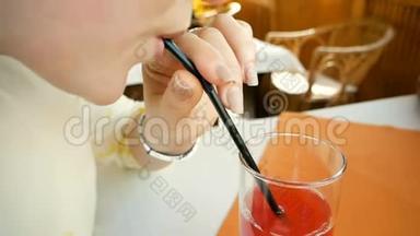 女孩从手里拿出一根烟斗，轻轻地从桌子上的玻璃杯里喝下果汁。