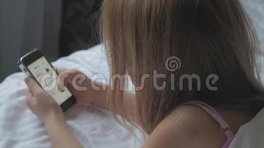 年轻女孩坐在床上，用电话做网上购物。 网上购物的概念。
