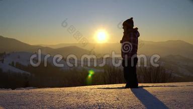 年轻的女游客站在雪地里。 她向丈夫招手，他们一起欣赏日落。