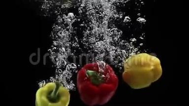 鲜红色和黄色的甜椒缓慢地落入水中，黑色背景