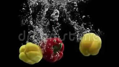 红、黄胡椒<strong>落入</strong>水中，在黑色背景上旋转气泡