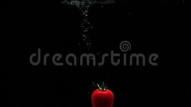 新鲜成熟的西红柿<strong>落入</strong>干净的水中，气泡和黑色背景上的水滴