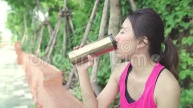 健康美丽的年轻亚洲跑步女子饮水，因为在城市公园街头跑步后感到疲倦。