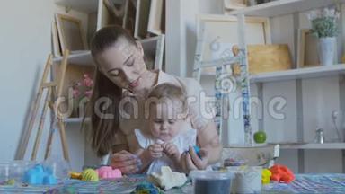 一位年轻开朗的母亲和她的孩子在玩软塑料。 宝宝试着吃塑料