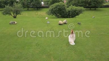 幸福的新娘在绿草上跳舞，背景是高山和果园