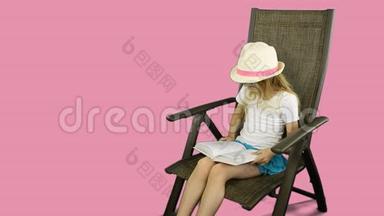 年轻的白种人女孩穿着白色的t恤和帽子坐在椅子上仔细阅读书籍。