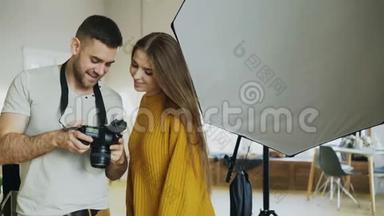 专业摄影师，男子在摄影棚的私人工作室向学生女孩展示数码相机照片