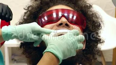 一个人在牙医那里准备牙齿<strong>美白</strong>的录像，牙医给他一个口腔道具