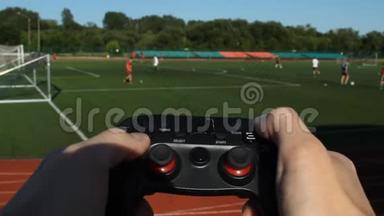这名男子点击体育场背景上的游戏操纵杆和足球比赛的按钮，特写。