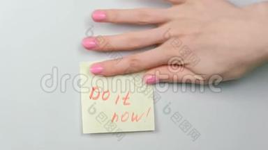 特写女人`她的手贴着黄色的贴纸纸，上面写着字。
