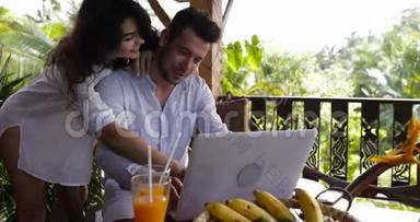 年轻夫妇在夏季森林的露台上使用笔记本电脑，美丽的男人和女人一起<strong>上网聊天</strong>