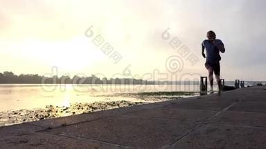勇敢的运动员在斯隆莫的日落处用混凝土板在河岸上奔跑