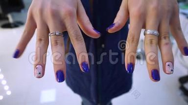 手特写。修指甲。蓝色指甲油。一个小女孩在镜头上展示她的美甲，这是为她做的