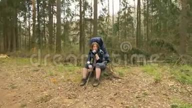 一个美丽的女孩坐在树桩上，在一个夏天的森林飞行相机拍摄