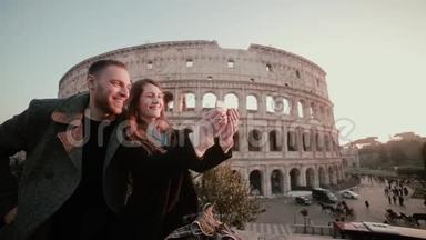快乐的年轻夫妇在意大利罗马斗兽场附近自拍。 旅行的男人和女人在镜头里微笑。