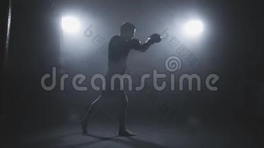在烟雾弥漫的工作室进行泰拳训练。 拳击手冲拳