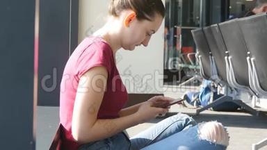 年轻女子在机场<strong>候机厅</strong>使用智能手机。 有智能手机的女孩在<strong>候机厅</strong>等待飞行