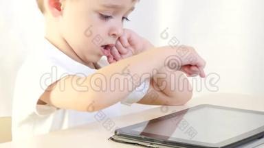 快乐的孩子坐在桌子旁，玩平板电脑。 孩子乐于玩电子游戏.. 儿童的概念