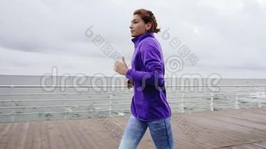 近距离观看年轻的运动女子在海边的长廊上慢动作地在户外<strong>跑步</strong>，享受清晨的<strong>跑步</strong>