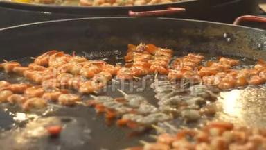 烤虾在一个大煎锅里煎。 烧烤时炸海鲜。 在街头美食节上炸虾。 烧烤