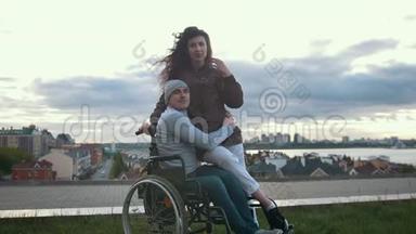 一位<strong>坐</strong>轮椅的快乐残疾人与户外年轻女子<strong>拥</strong>抱的肖像
