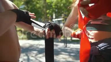 运动型高加索人男子和女子用绷带包扎双手，在夏季公园进行训练，动作缓慢