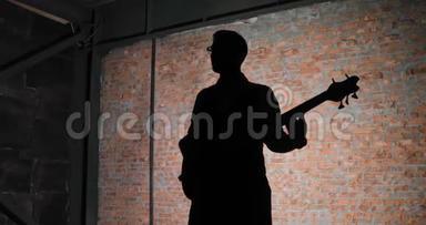 吉他手的剪影，砖墙背景