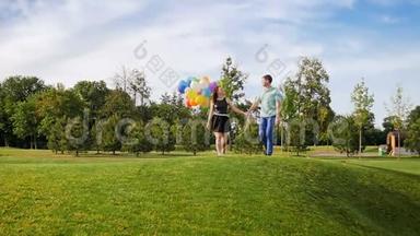一对幸福的年轻夫妇带着一堆五颜六色的<strong>气球</strong>在公园散步的慢动作<strong>视频</strong>